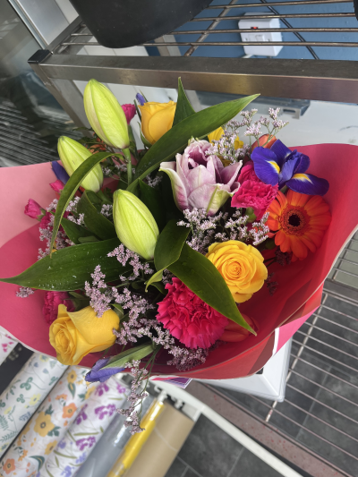 Bright & Beautiful - A lively bouquet of vibrant orange, red and pink tones, softened with fresh greenery and touches of white.