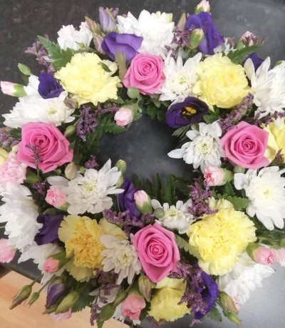 Pastel Wreath - A beautiful funeral wreath in pink, purple, soft yellow and white tones, thoughtfully arranged as a heartfelt tribute.