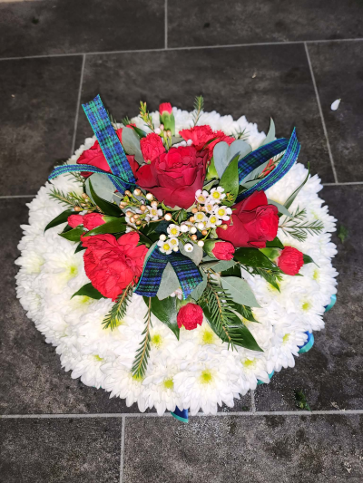 Posy in Oasis - A classic round funeral tribute with rich, warm colours and traditional tartan detailing for a personal finishing touch.